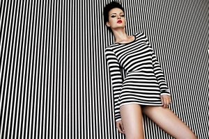 Brunette woman wearing a stripy dress on a stripy background